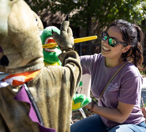 HSDA Chapter President Esmeralda Diaz, RDH, shows a kid how to properly brush teeth on a dragon stuffed animal.